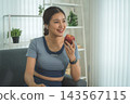 Active Asian Woman Exercising, Stretching and Tracking Fitness During a Healthy Home Workout 143567115