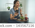 Active Asian Woman Exercising, Stretching and Tracking Fitness During a Healthy Home Workout 143567116