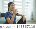 Active Asian Woman Exercising, Stretching and Tracking Fitness During a Healthy Home Workout 143567119