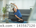 Active Asian Woman Exercising, Stretching and Tracking Fitness During a Healthy Home Workout 143567120