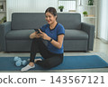 Active Asian Woman Exercising, Stretching and Tracking Fitness During a Healthy Home Workout 143567121