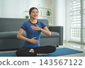 Active Asian Woman Exercising, Stretching and Tracking Fitness During a Healthy Home Workout 143567122