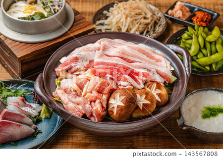 一張照片展現了居酒屋(日式酒吧)宴會桌上的盛宴,包括豐盛的火鍋、生魚片和各種小菜。 一張照片展現了居酒屋(日式酒吧)宴會桌上的盛宴,包括豐盛的火鍋、生魚片和各種小菜。 143567808