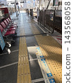日本火車站月台，設有紅色長椅和黃色盲道。 143568058