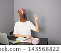 A Humorous Scene Featuring a Person with a Horse Mask Engaging in a Quirky Work Environment with Writing Tools and a Mug 143568822