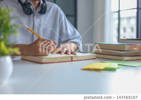 College Student Writing Research Notes During Online Learning and Academic Study Session at Home. College Student Writing Research Notes During Online Learning and Academic Study Session at Home. 143569107