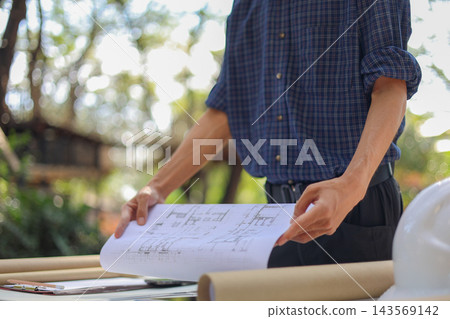 Civil engineer or site manager reviewing construction blueprints outdoors on a construction site Civil engineer or site manager reviewing construction blueprints outdoors on a construction site 143569142