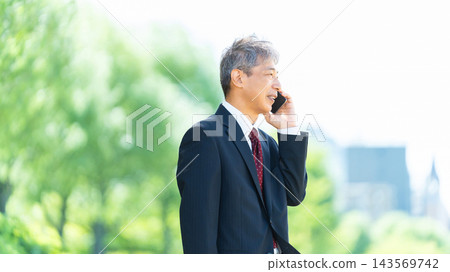 Senior male businessman making a phone call on his smartphone 143569742