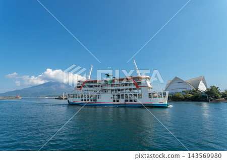 A ferry sailing across Kinko Bay with the summer blue sky and Sakurajima volcano as a backdrop, and the Kagoshima Aquarium. A ferry sailing across Kinko Bay with the summer blue sky and Sakurajima volcano as a backdrop, and the Kagoshima Aquarium. 143569980