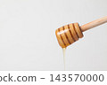 Honey dripping from a honey dipper against a white background. 143570000