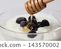 Pour honey over the blueberry yogurt using a honey dipper. 143570002