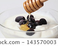 Pour honey over the blueberry yogurt using a honey dipper. 143570003