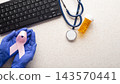 Medical Professional Holding Pink Breast Cancer Awareness Ribbon at Desk 143570441