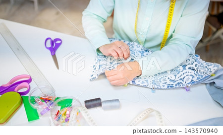 Seamstress hands crafting lace fabric in sewing workshop 143570940