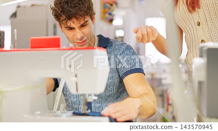 Young man learning sewing in atelier with instructor Young man learning sewing in atelier with instructor 143570945