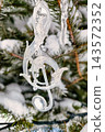 A Christmas and New Year tree is decorated with ornaments and surrounded by snow. The tree shows signs of festive celebration during the holiday season 143572352