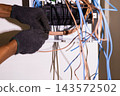 Electrician bundling and organizing electrical wires inside a circuit breaker. 143572502