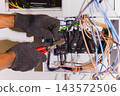Electrician using wire cutters to strip and electrical wiring. 143572506