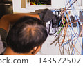 Electrician working on electrical panel wiring and circuit breaker installation. 143572507