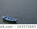 Small Blue Rowboat Floating on Water with Large Copy Space 143572665