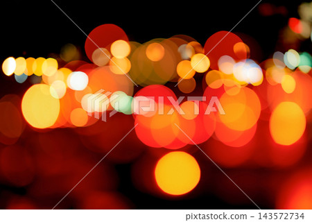 Blurred red and orange bokeh background. Blur abstract background of urban light. Warm light with beautiful pattern of round bokeh. Light in the night. Street lamp lights in the city at dark night. 143572734