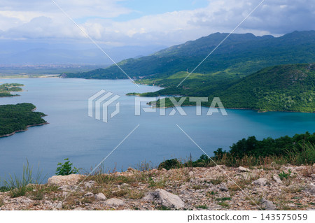 Panoramic Mountain Lake Landscape With Turquoise Water, Rocky Foreground and Lush Green Coastline 143575059