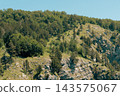 Sunlit Mountain Forest And Rocky Hillside With Scattered Pine Trees Under Blue Sky 143575067