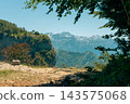 Scenic Mountain View From Forested Cliff Overlooking Snow-Capped Peaks and Valley Trail 143575068