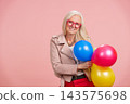 Senior woman celebrating lively aging holding balloons 143575698