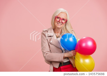 Senior woman celebrating lively aging holding balloons 143575698