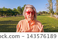 Mature woman wearing star glasses talking outdoors in park 143576189