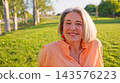 Senior woman smiling in park enjoying sunset light 143576223