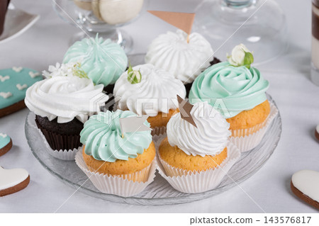 Assorted wedding cupcakes with white and mint cream frosting and decorative flags on glass plate 143576817