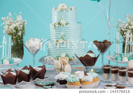 Three tiered mint birthday cake with cupcakes macarons and cake pops on dessert table Three tiered mint birthday cake with cupcakes macarons and cake pops on dessert table 143576818