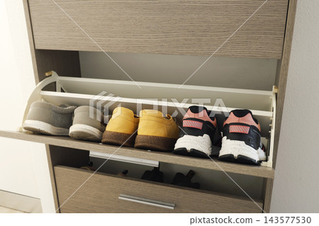 Wooden shoe cabinet organizer holds sneakers in open drawer unit. Functional entryway storage solution modern home interior order. Space saving tidy hallway furniture idea. Wooden shoe cabinet organizer holds sneakers in open drawer unit. Functional entryway storage solution modern home interior order. Space saving tidy hallway furniture idea. 143577530