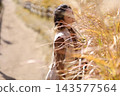 A woman closing her eyes amidst pampas grass 143577564