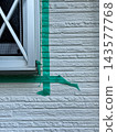 Applying masking tape around window frames during exterior wall painting sealing work. 143577768