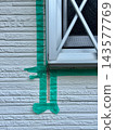 Applying masking tape around window frames during exterior wall painting sealing work. 143577769