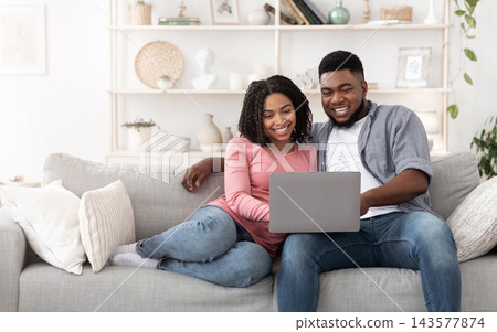 Weekend Passtime. Married African American Couple Using Laptop At Home Together, Relaxing On Couch In Living Room, Watching Movies, Copy Space Weekend Passtime. Married African American Couple Using Laptop At Home Together, Relaxing On Couch In Living Room, Watching Movies, Copy Space 143577874