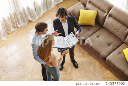 Above view of real estate agent communicating with customers about house purchase or rent indoors Above view of real estate agent communicating with customers about house purchase or rent indoors 143577902