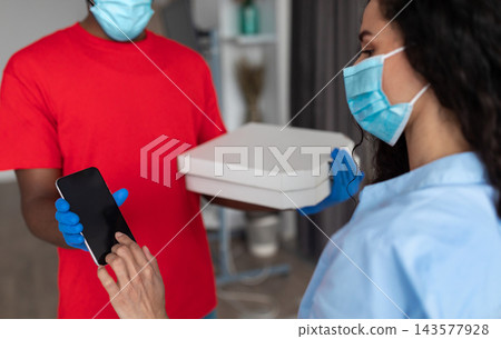 Courier Service, Safety Concept. Customer In Protective Medical Face Mask Signing Electronic Form Or Receipt After Receiving Order Using Mobile Phone, Delivery Guy Holding Cardboard Pizza Boxes Courier Service, Safety Concept. Customer In Protective Medical Face Mask Signing Electronic Form Or Receipt After Receiving Order Using Mobile Phone, Delivery Guy Holding Cardboard Pizza Boxes 143577928