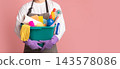 Bucket with cleaning supplies and tools in hands of unrecognizable man in apron standing on pink background, cropped image, panorana with free space 143578086