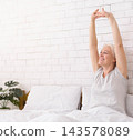 Good rest. Cheerful well-slept senior lady stretching in bed in morning, empty space 143578089