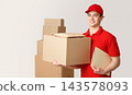 Courier and package in warehouse. Smiling deliveryman holding big box and tablet under his arm near stack of parcels, panorama, studio shot 143578093