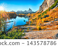 Amazing autumn view of  Lake Federa  at sunrise with majestic rocky mount and colorful trees glowing sunlight in Dolomites 143578786