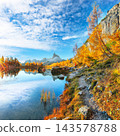 Amazing autumn view of  Lake Federa  at sunrise with majestic rocky mount and colorful trees glowing sunlight in Dolomites 143578788