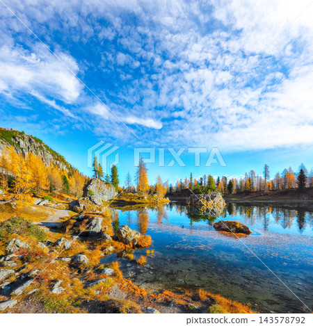 Amazing autumn view of Lake Federa at sunrise with majestic rocky mount and colorful trees glowing sunlight in Dolomites Amazing autumn view of Lake Federa at sunrise with majestic rocky mount and colorful trees glowing sunlight in Dolomites 143578792