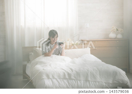 在床上看智能手機的女人 在床上看智能手機的女人 143579036