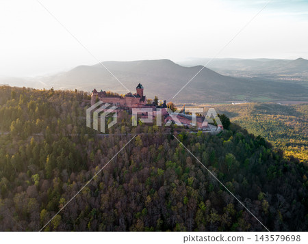 Sunrise silhouette of hilltop fortress. Castle Haut-Koenigsbourg, Alsace, France - April 10, 2026 - Sunrise silhouette of hilltop fortress, long shadows stretching across valleys, crisp air, lens flar Sunrise silhouette of hilltop fortress. Castle Haut-Koenigsbourg, Alsace, France - April 10, 2026 - Sunrise silhouette of hilltop fortress, long shadows stretching across valleys, crisp air, lens flar 143579698