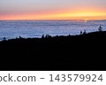 Warm sunset light spreads across a sea of clouds below the ridge in Teide National Park. Perspective and calm for wellbeing travel and mental reset campaigns. 143579924